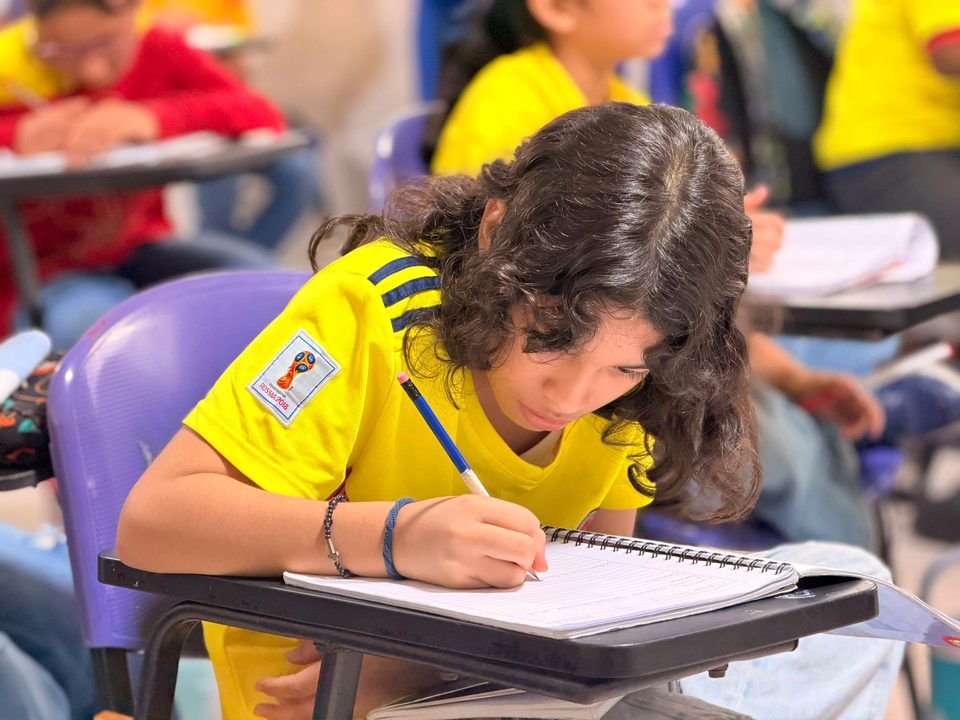 Estudiante de primaria escribiendo en clase